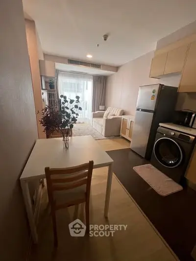 Cozy studio apartment with modern kitchen and living area, featuring a washing machine and fridge.