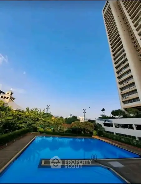 Luxurious high-rise building with stunning pool and lush greenery, perfect for urban living.