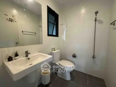 Modern bathroom with sleek fixtures and minimalist design, featuring a wall-mounted sink and shower.