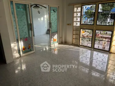 Spacious living room with large windows and sliding glass doors, offering abundant natural light and garden view.