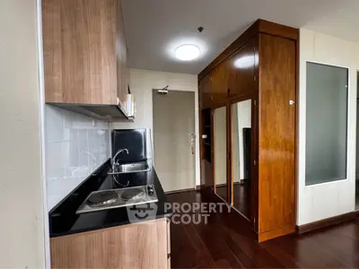 Modern kitchen with sleek wooden cabinets and compact electric stove in stylish apartment.