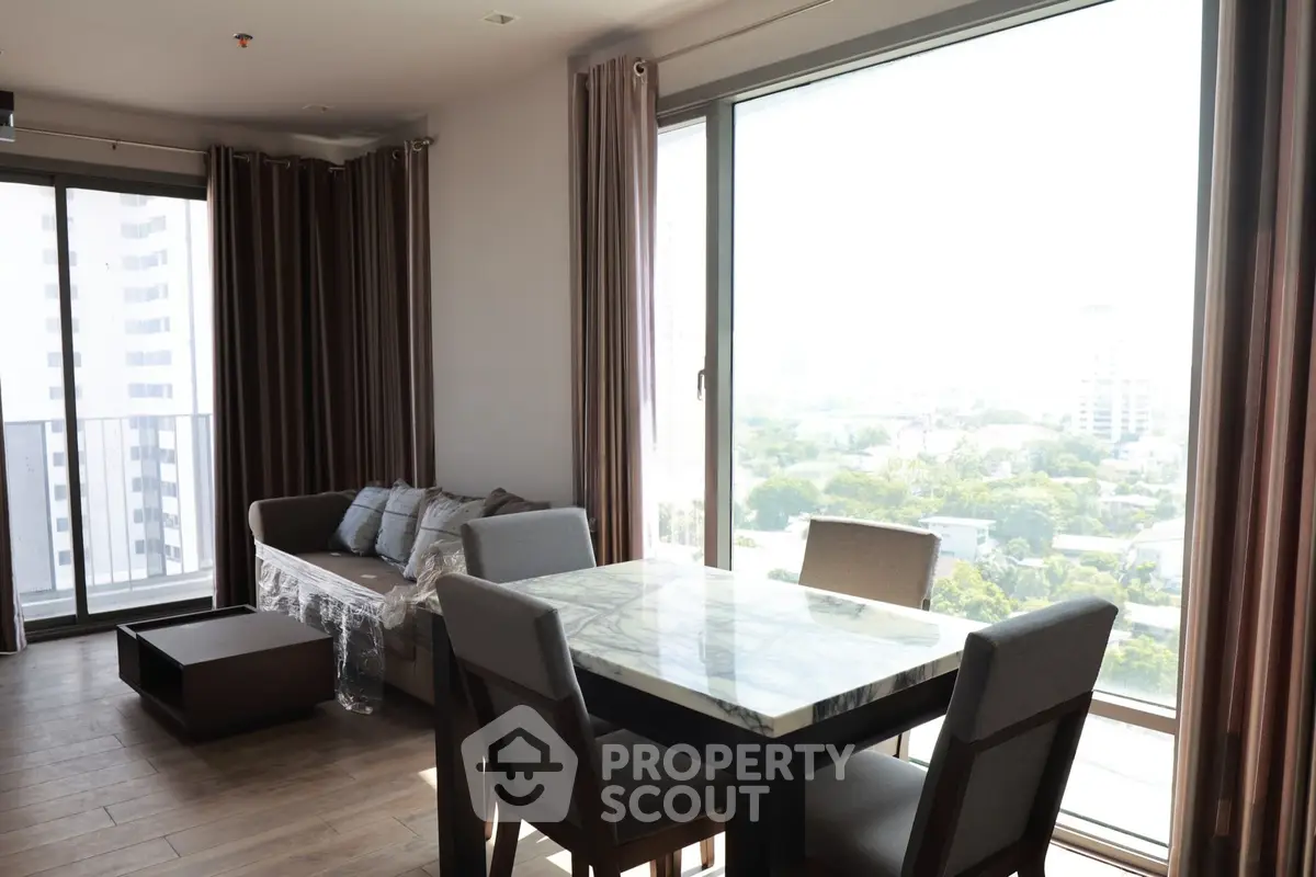 Spacious living room with large windows and modern furniture offering a stunning city view.