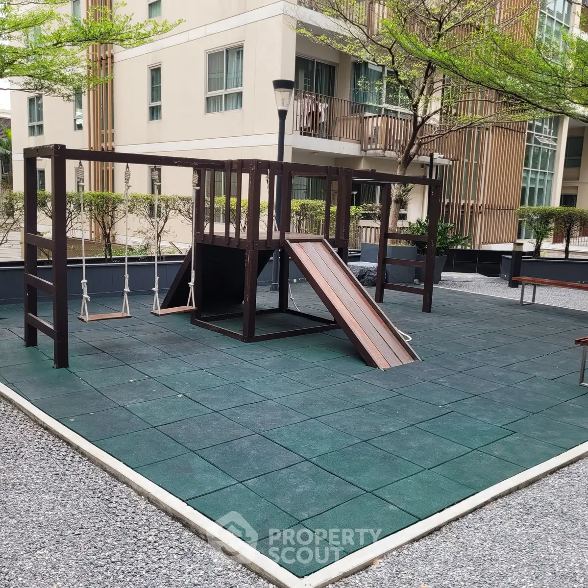 Modern apartment building with outdoor playground and lush greenery