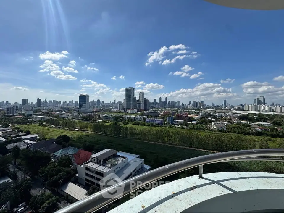 Stunning cityscape view from a high-rise balcony showcasing urban skyline and lush greenery.