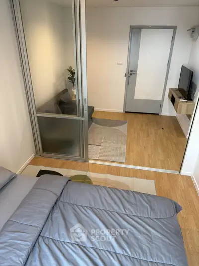 Modern studio apartment with cozy bedroom and living area separated by glass partition.