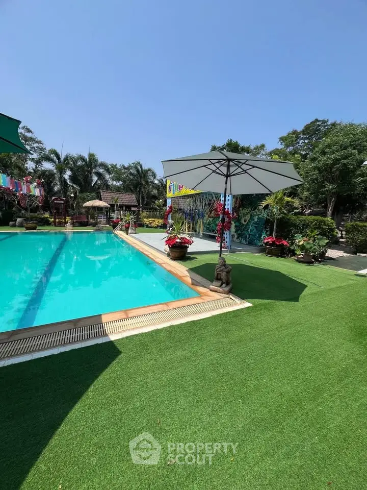 Luxurious outdoor pool area with lush greenery and stylish umbrellas, perfect for relaxation and leisure.