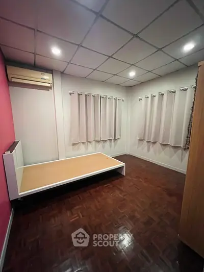 Spacious bedroom with wooden flooring and modern air conditioning unit.