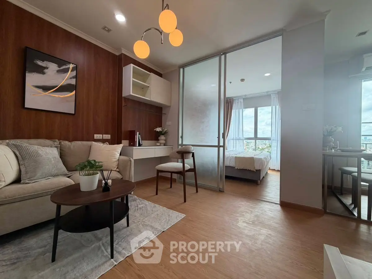 Modern living room with wooden flooring and cozy decor leading to a bright bedroom with city views.