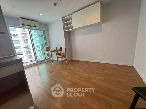 Spacious living room with wooden flooring and balcony access in modern apartment.