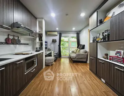 Modern kitchen with open layout and cozy living area, featuring stylish cabinetry and natural light.