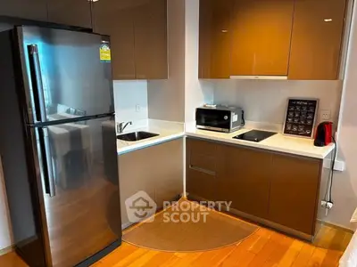 Modern kitchen with sleek cabinets, stainless steel fridge, and compact appliances in a cozy apartment.