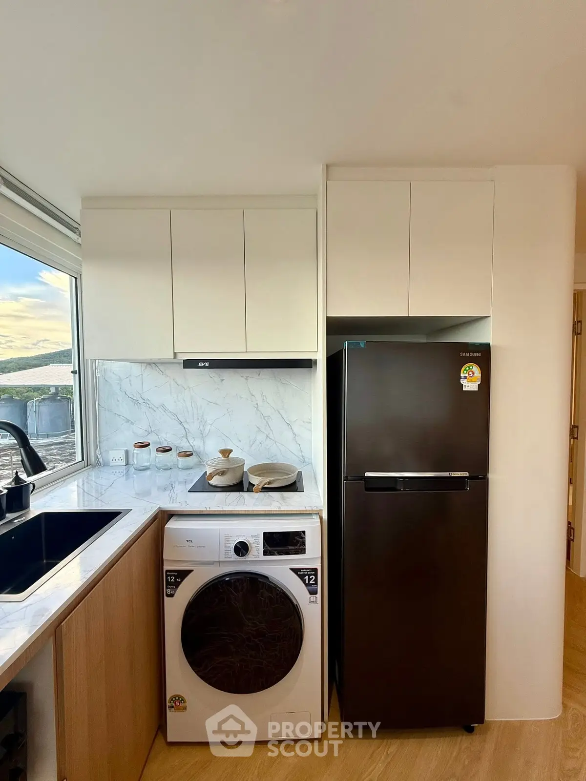 Modern kitchen with sleek appliances and marble backsplash, featuring a washing machine and fridge.