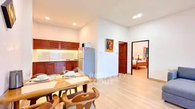 Modern open-plan living room and kitchen with wooden furniture and bright lighting.