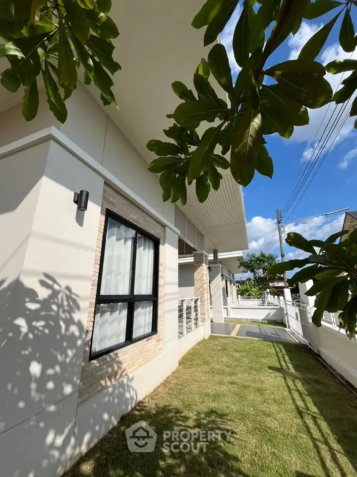 Modern house exterior with lush garden and clear blue sky, showcasing contemporary architecture and inviting outdoor space.