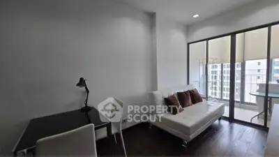 Modern living room with sleek furniture and balcony view in a high-rise apartment.