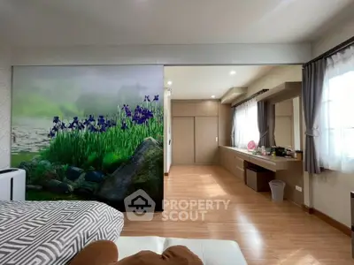 Spacious bedroom with artistic wall mural and ample natural light