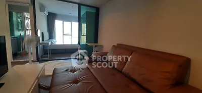 Modern living room with brown leather sofa and glass partition leading to bedroom.