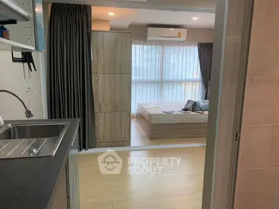 Modern studio apartment with open layout, featuring a compact kitchen and cozy bedroom area.