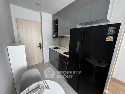 Modern compact kitchen with sleek appliances and dining area in a stylish apartment.