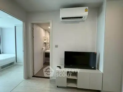 Modern apartment interior with air conditioner and TV, showcasing minimalist design and neutral tones.