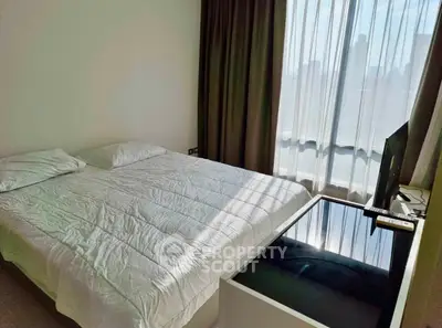 Spacious bedroom with large window and modern decor in a city apartment.