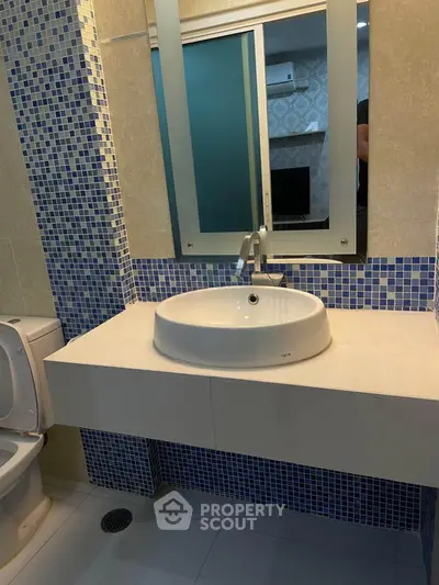 Modern bathroom with stylish blue mosaic tiles and sleek white fixtures.