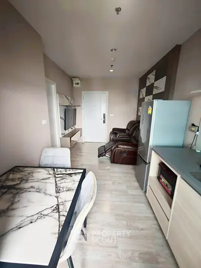 Modern apartment interior with sleek kitchen and cozy living area featuring marble dining table and leather recliner.
