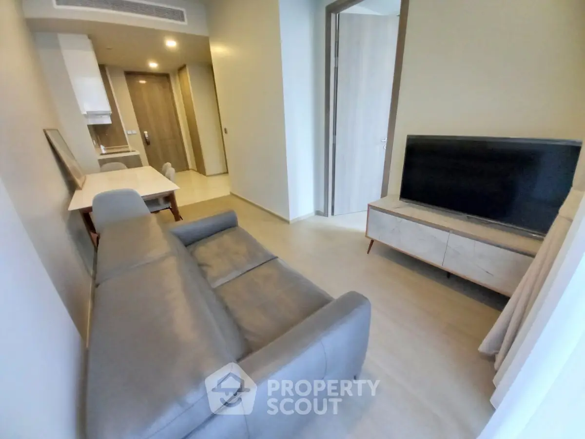 Modern living room with sleek furniture and open kitchen layout in a stylish apartment.