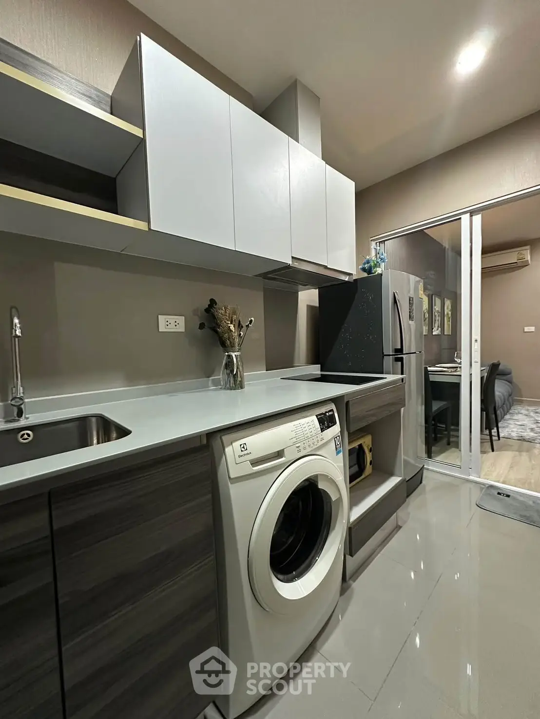 Modern kitchen with sleek cabinetry and built-in washing machine in stylish apartment.