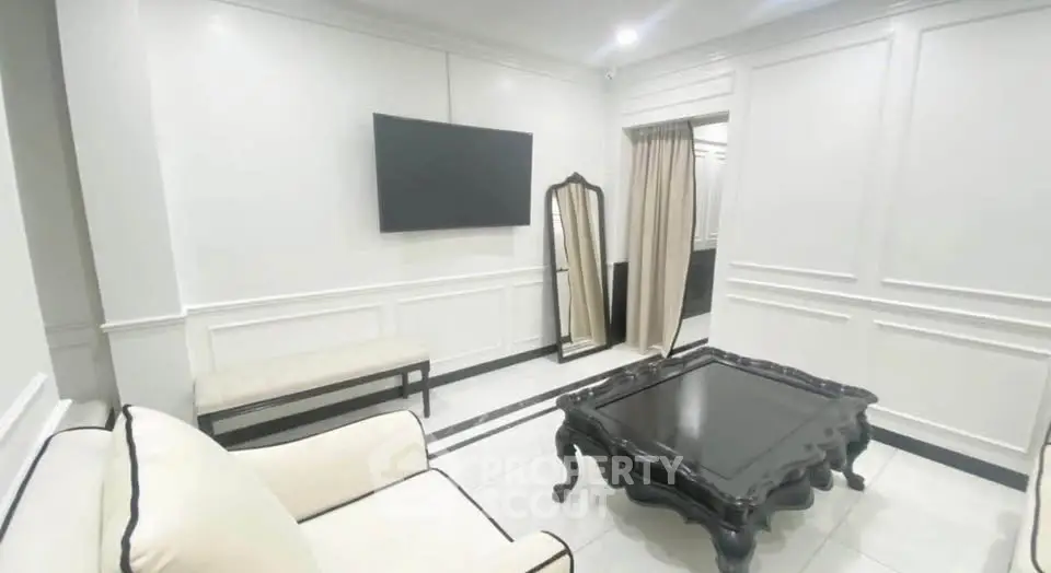 Elegant living room with classic black and white decor, featuring a wall-mounted TV and stylish furniture.