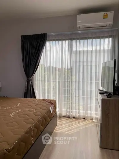 Cozy bedroom with natural light, featuring a large window, air conditioning, and modern furnishings.