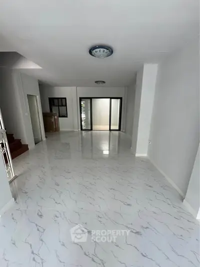Spacious modern living room with marble flooring and large sliding glass doors.