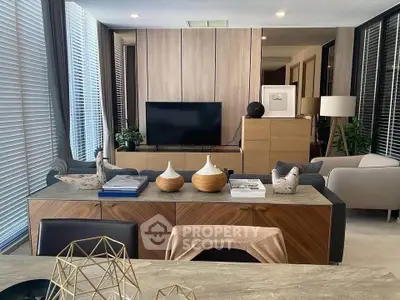 Modern living room with stylish decor and large windows, featuring a sleek TV setup and elegant furniture.