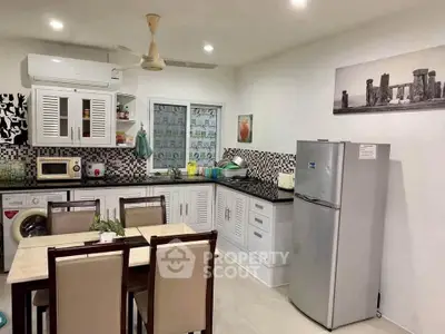 Modern kitchen with dining area, featuring appliances and stylish cabinetry.