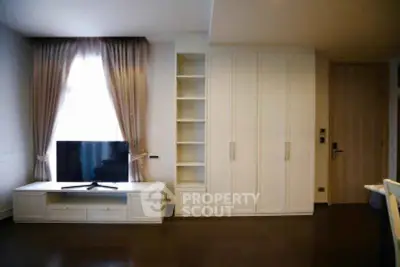 Modern living room with elegant curtains, built-in storage, and flat-screen TV.