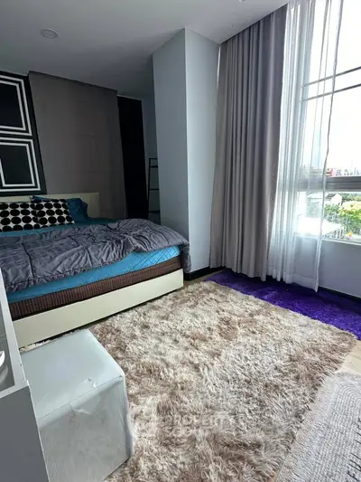 Modern bedroom with plush carpet and large window offering natural light.
