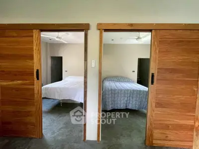 Modern dual bedroom setup with sliding wooden doors and ceiling fans.
