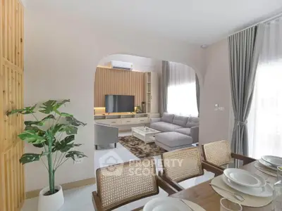 Modern living room with stylish decor and dining area, featuring a cozy sofa and large TV.