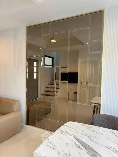 Modern living room with elegant decor and stylish furniture, featuring a marble table and mirrored wall.
