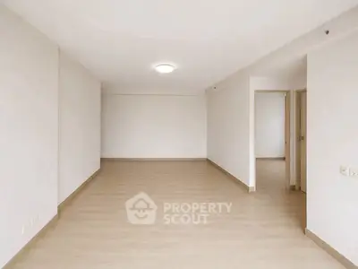 Spacious empty living room with light wood flooring and neutral walls, ideal for customization.
