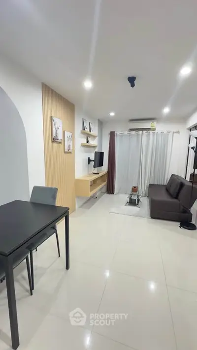 Modern living room with sleek furniture and minimalist decor, featuring a cozy sofa and wall-mounted TV.