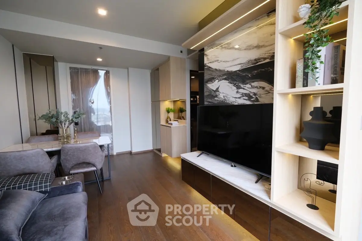 Modern living room with elegant decor, large TV, and stylish dining area in open layout apartment.