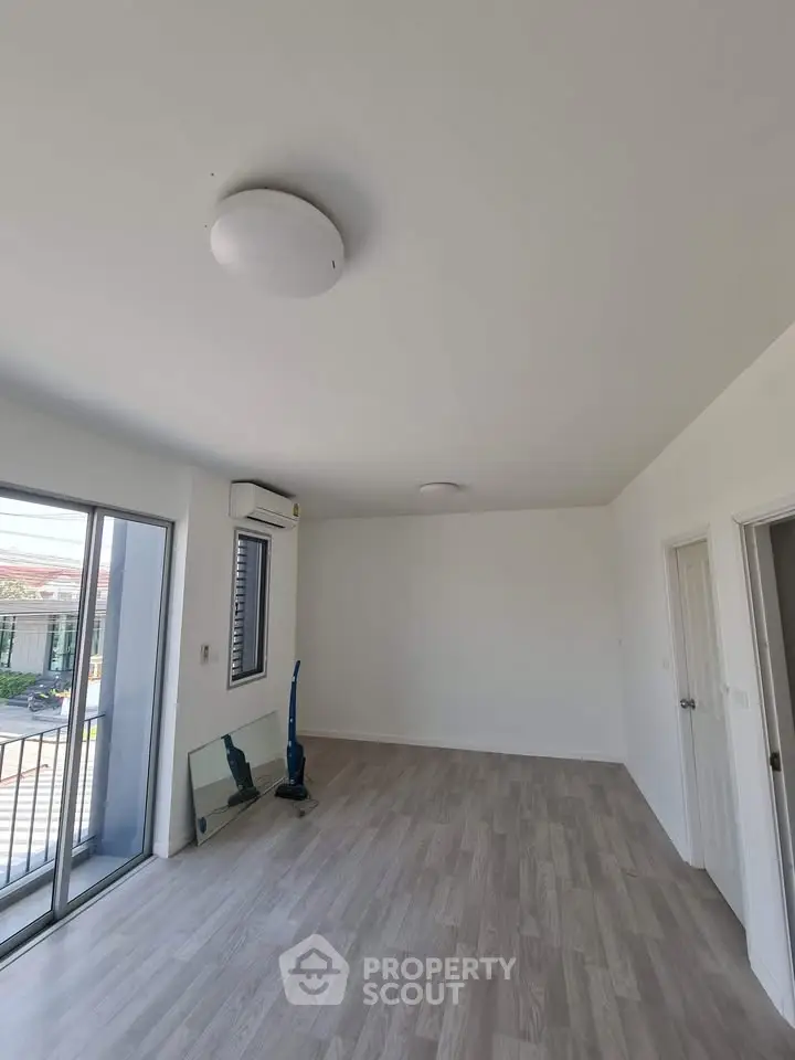 Spacious empty room with balcony access and modern flooring