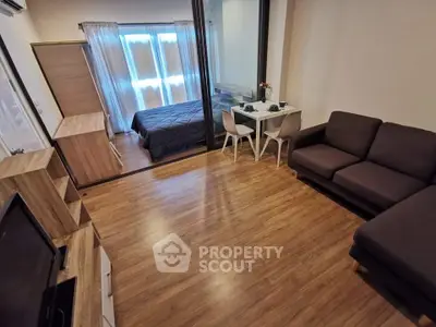 Modern studio apartment with cozy living area and bedroom, featuring wooden flooring and stylish furniture.