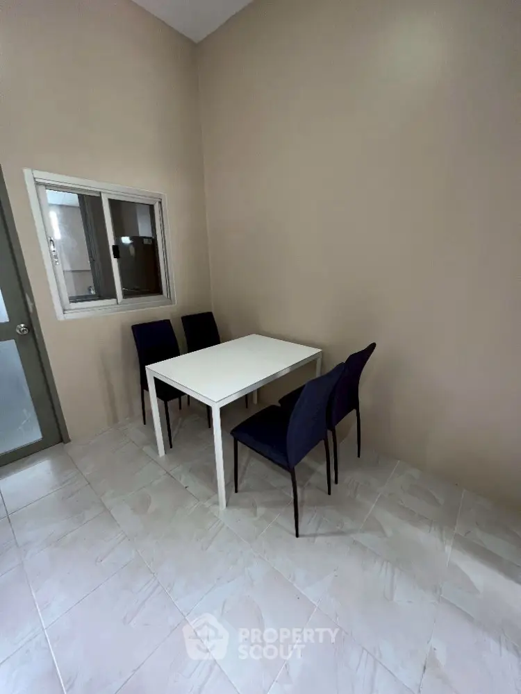 Minimalist dining area with white table and dark chairs in a cozy corner setting.