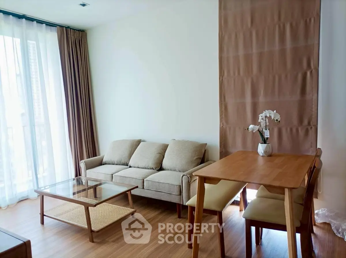 Modern living room with elegant furniture and natural light, featuring a cozy sofa and dining area.