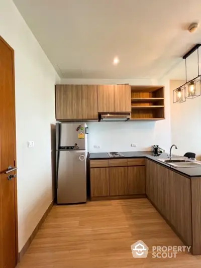 Modern kitchen with wooden cabinets and stainless steel fridge in open layout