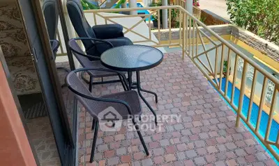 Charming balcony with pool view, featuring cozy seating and elegant railing design.