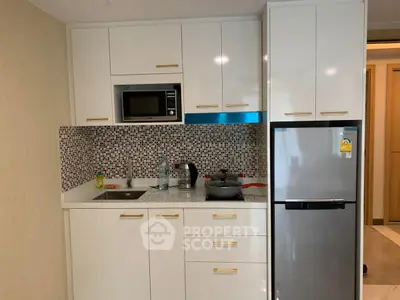 Modern compact kitchen with sleek white cabinets and built-in appliances in a stylish apartment.