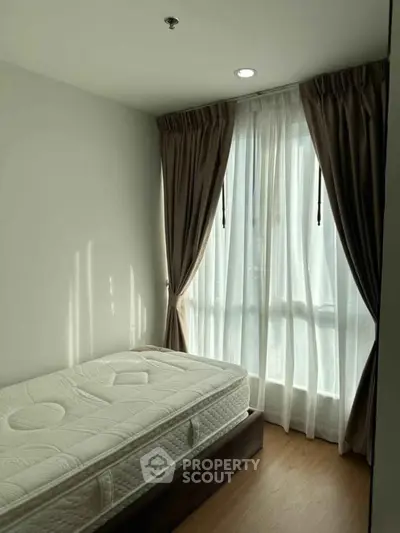 Cozy bedroom with natural light and elegant curtains, perfect for relaxation.